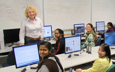 adult students sitting at computers with teacher